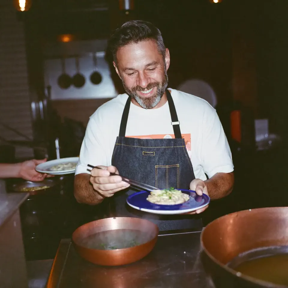 Chef-owner plating a dish during evening service while his reviews get answered