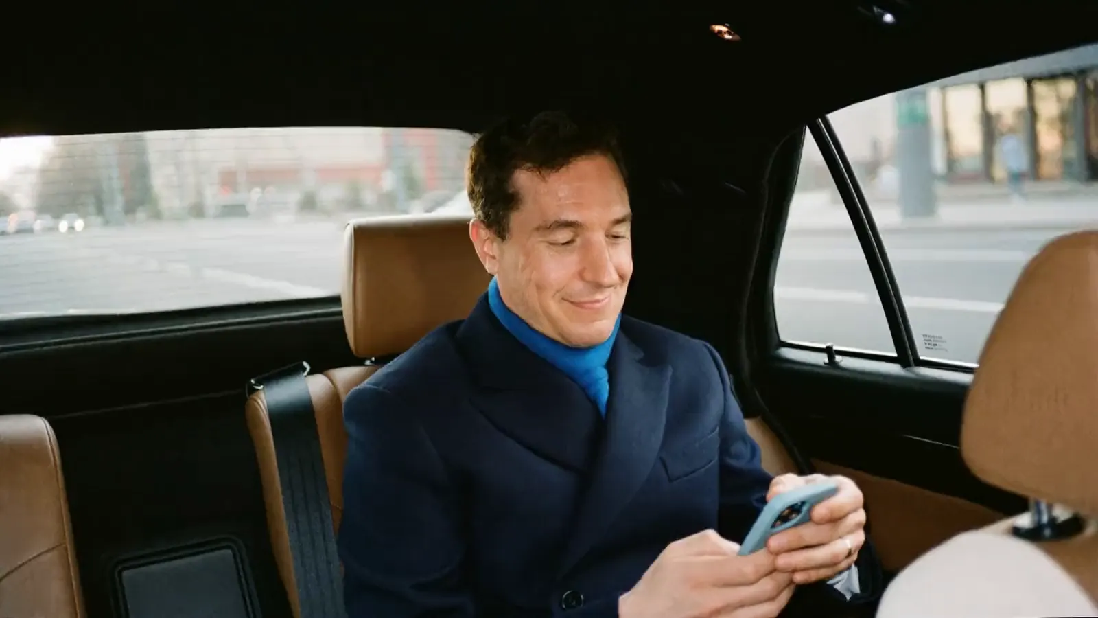 Executive reading his phone in the back of a car