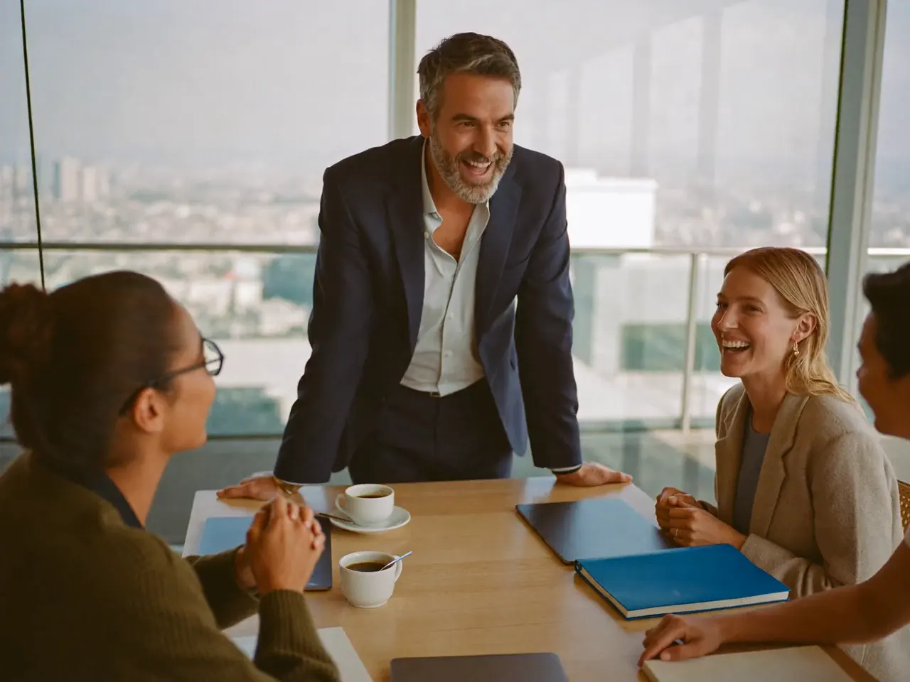 Founder standing at the head of the table, laughing with his leadership team on a Monday morning